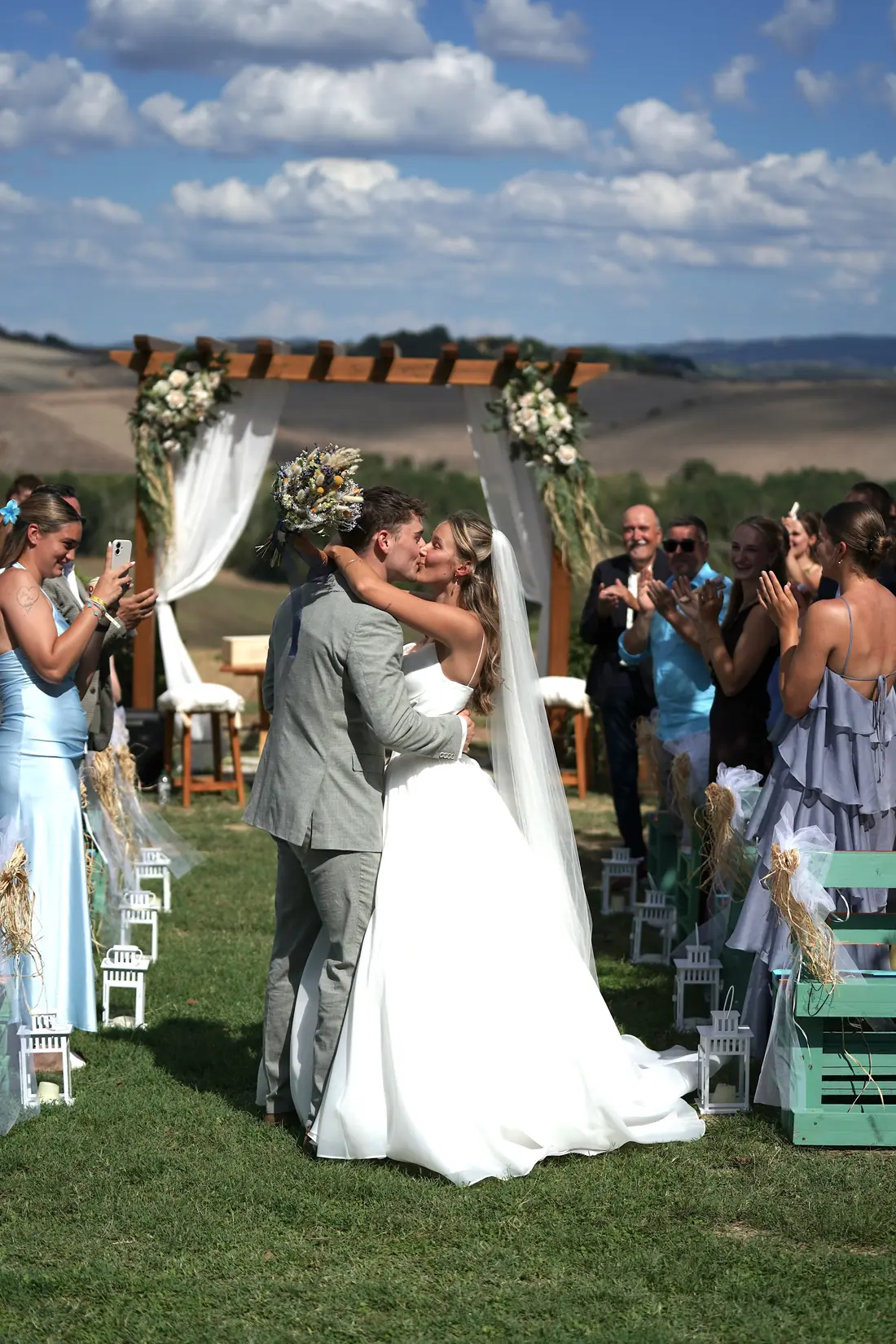 The newlyweds kiss after the ceremony, surrounded by their guests