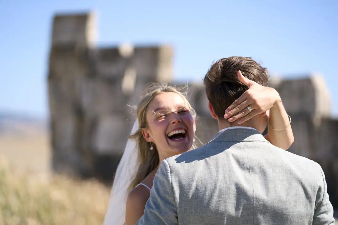 The bride laughing, embraced by the groom