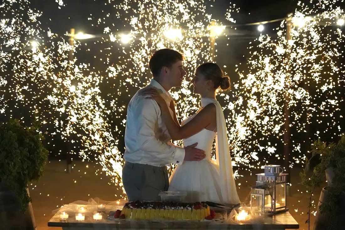 Bride and groom cutting the cake between sparkling fountains